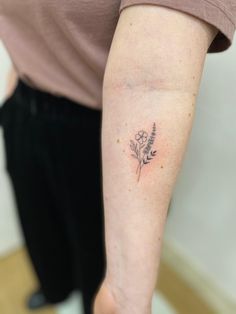 a woman's arm with a small flower tattoo on the left side of her arm