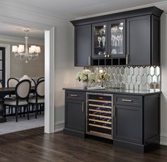 a dining room and kitchen area with wine glasses on the bar, chandelier in the background