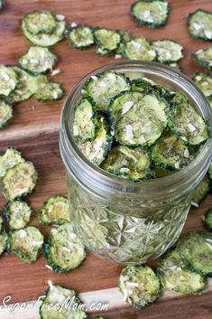 a glass jar filled with sliced cucumbers on top of a wooden cutting board