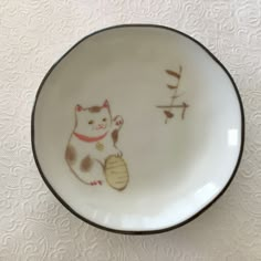 a white and brown plate with a cat on it