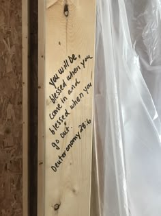 a piece of wood with writing on it and some plastic covering the wall behind it