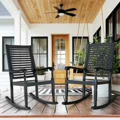 two black rocking chairs sitting on top of a wooden floor next to a porch with a ceiling fan