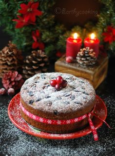 a cake sitting on top of a red plate next to pine cones and christmas decorations