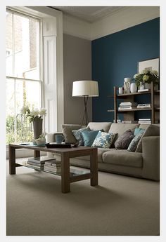 a living room filled with furniture next to a large window covered in blue and white pillows