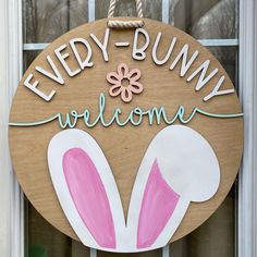 a wooden sign that says, every bunny welcomes with pink and white painted ears