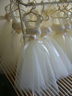 four white tulle dresses hanging on a rack with ribbons and bows around the waist