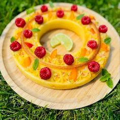 a cake with raspberries and lime slices on a wooden plate in the grass