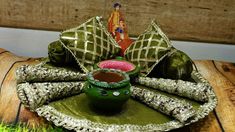 a green pot with a pink candle on top of it sitting on a wooden table