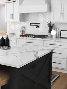 a kitchen with white cabinets and marble counter tops, along with an island in the middle