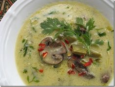 a bowl of soup with mushrooms, peppers and parsley in it on a table