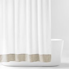 a white shower curtain with a brown stripe on the side and a cup next to it