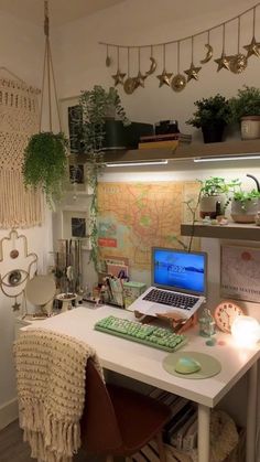 a laptop computer sitting on top of a white desk next to a plant filled wall