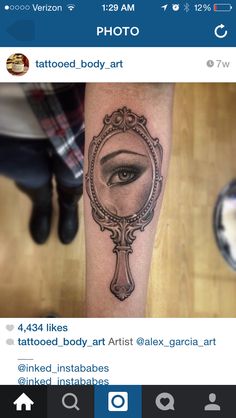 a woman's eye reflected in a mirror tattoo on the leg, with an ornate frame around it