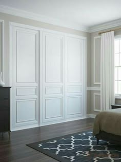 a bedroom with white paneled walls and wood flooring, along with a large bed