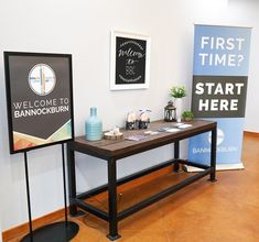 two signs are displayed on the wall next to each other in front of a wooden table