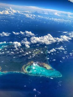 an aerial view of the ocean with clouds and landforms in the foreground, taken from above