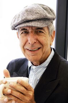 an older man wearing a hat and holding a cell phone in his hand while smiling at the camera