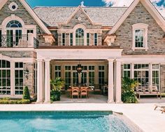 a large house with a pool in the front yard and an outdoor dining area next to it