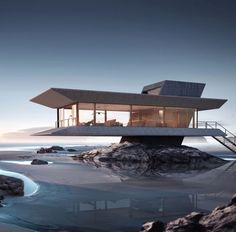 a house on top of a rock by the ocean at dusk with water running through it