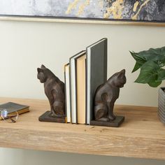 two bookends are sitting on a wooden shelf with books and a potted plant