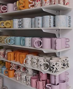 the shelves are filled with many different colored cups and mugs on it's sides