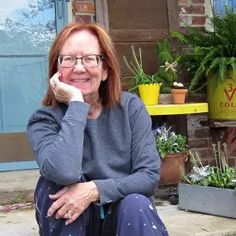 a woman sitting on the steps in front of some potted plants and smiling at the camera