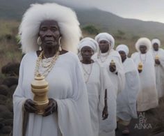 a group of women dressed in white standing next to each other on a dirt road