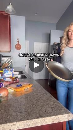 a woman standing in a kitchen holding a frying pan