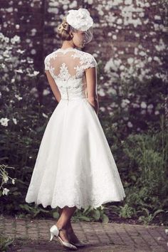 the back of a woman's wedding dress, with white flowers in the background