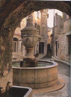 a stone fountain in the middle of an alley way