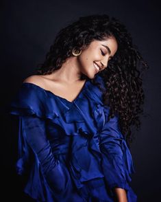 a woman with curly hair wearing a blue dress