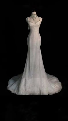 a white wedding dress on display in the dark