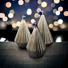 two silver vases sitting on top of a table next to a blurry background