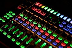 an electronic mixing board lit up in the dark with colored lights on it's sides