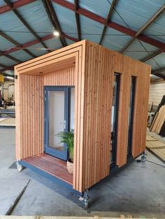 a small wooden building with doors and windows on the outside, in a warehouse area