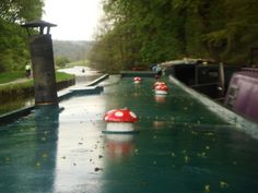 several boats are lined up along the side of a river with red caps on them