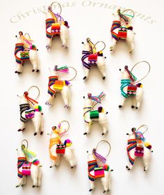 a group of llama ornament hanging from strings on a white wall with the words christmas ornaments written in it