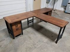 an office desk made out of wood and metal with two drawers on each side, in front of a garage door