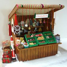 a christmas market stand with lots of food on it's display shelf and decorations hanging from the roof