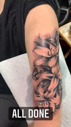 a woman's arm with flowers and butterflies tattooed on the side of her arm