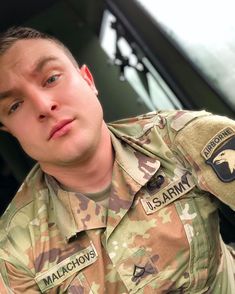 a close up of a person in uniform near a car and building with an eagle patch on his shirt