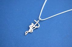 a silver necklace with a musical note in the shape of a treble on a blue background