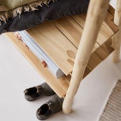 a pair of black shoes sitting on top of a wooden table next to a blanket