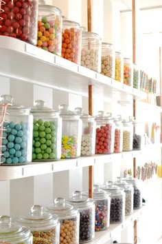 a shelf filled with lots of different types of candies and chocolates in glass jars