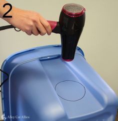 a person using a hair dryer on top of a blue container