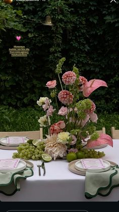 the table is set with flowers, grapes and other items for an elegant dinner party