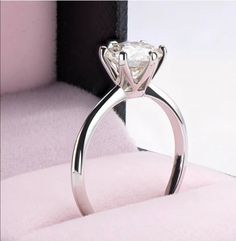 a white diamond ring sitting on top of a pink blanket