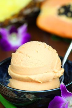 a bowl filled with ice cream next to a purple flower