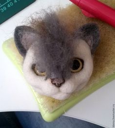 a needle - felted gray cat is sitting on a table next to a red pen