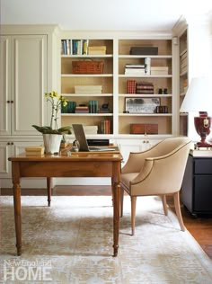 a desk with a laptop on it in front of a bookshelf full of books